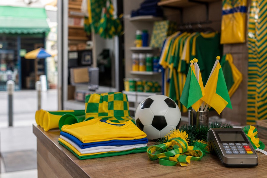 Balcao de pequeno comércio com decoração de futebol usado como capa sobre negócios na Copa